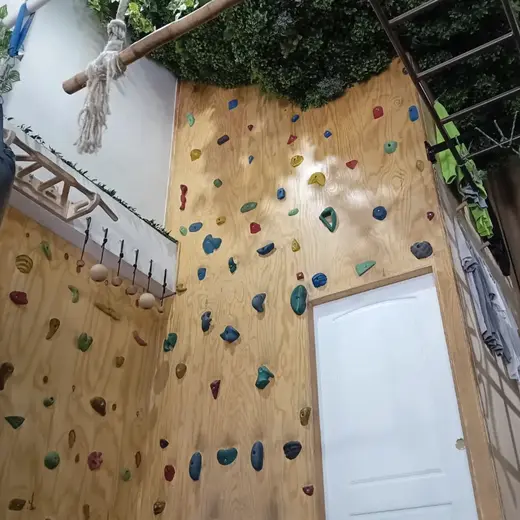 Paredes de escalada de madera con presas de colores, escalera y cuerda